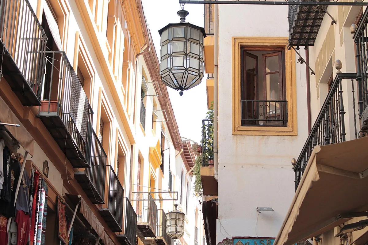 Decorative hanging lantern above a narrow Granada shopping street